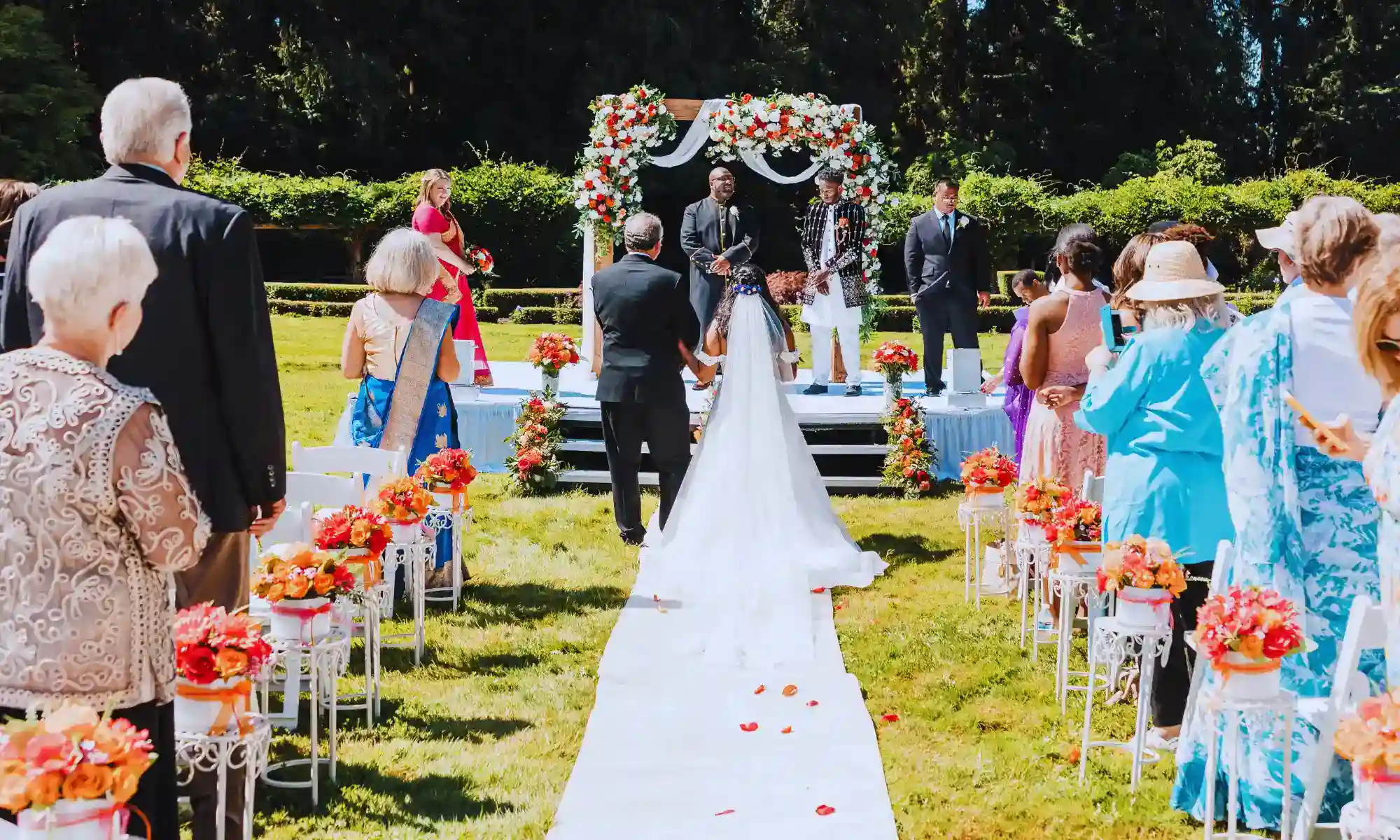Outdoor garden wedding ceremony at Carnation Farms with floral aisle, seated guests, and a decorated ceremony arch.